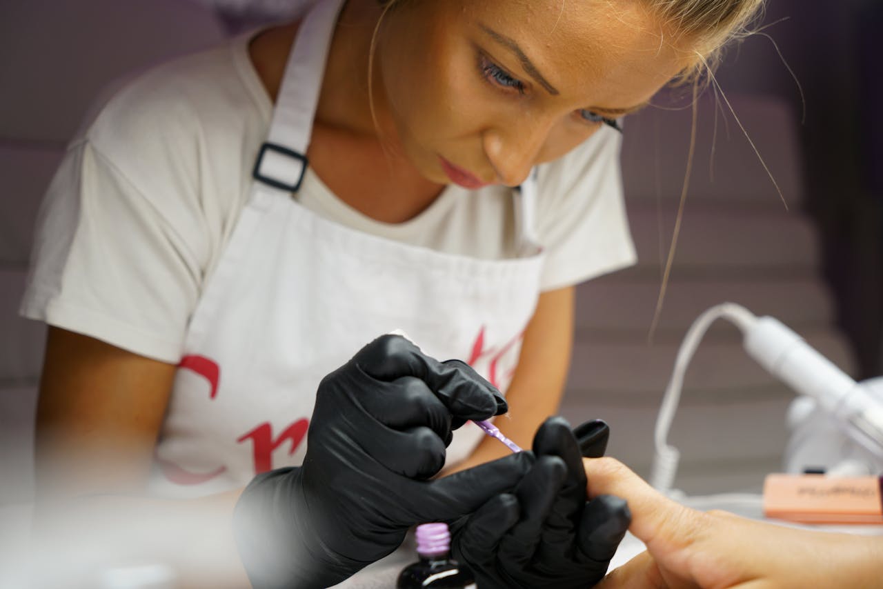 Nail artist focusing on intricate nail design for client in a salon.